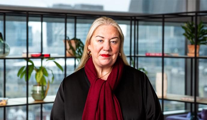 A portrait of Jen Tippin wearing a red scarf in a high-rise office building